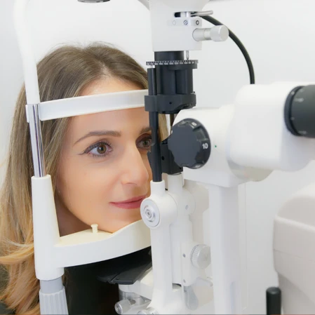 A patient leaning forward for a slit lamp exam