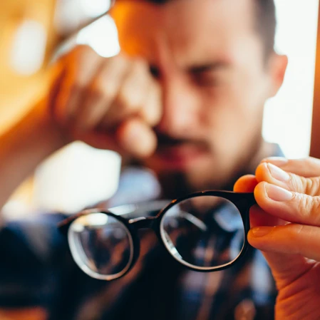 A patient with myopia rubbing at his strained eyes
